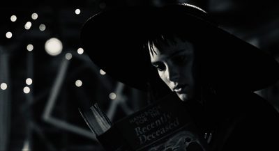 Black and white image of Lydia reading Handbook for the Recently Deceased in Beetlejuice (1988)
